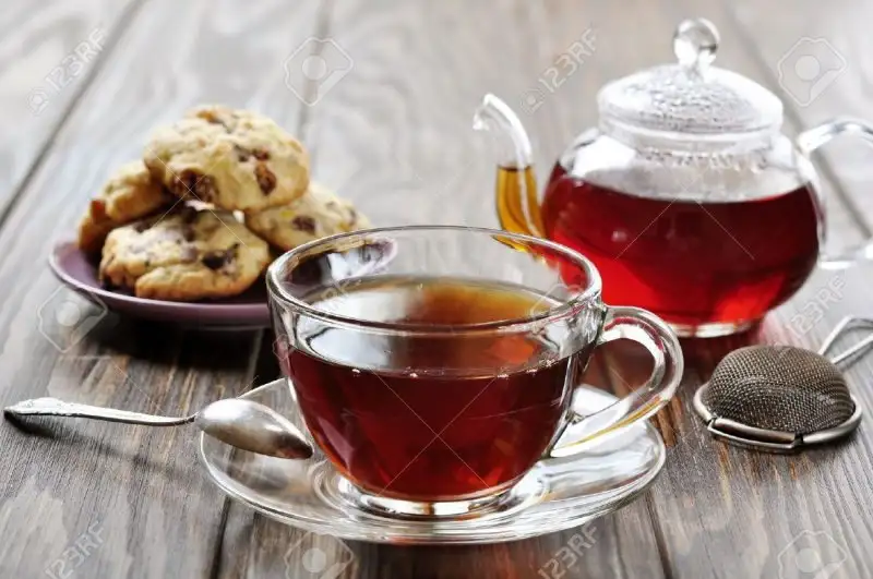 18681428-Cup-of-tea-with-teapot-and-cookies-on-wooden-background-Stock-Photo.webp