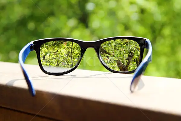 4405486_stock-photo-eyeglasses-in-the-hand-over-blurred-tree-background.webp